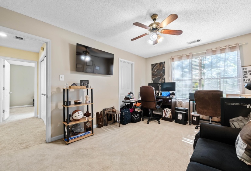 Carpeted room featuring a ceiling fan with integrated lighting, a large window with blinds, and recessed lighting in the hallway entry