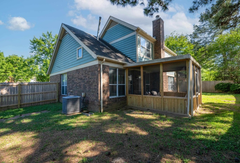 Exterior featuring brick and blue siding, a wooden privacy fence, a screened porch with natural wood paneling, and an HVAC unit