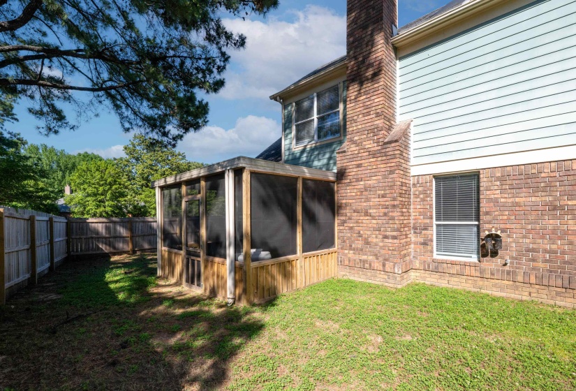 Exterior showcasing a screened porch with wood paneling, brick facade, light blue siding, and a privacy fence enclosing the yard
