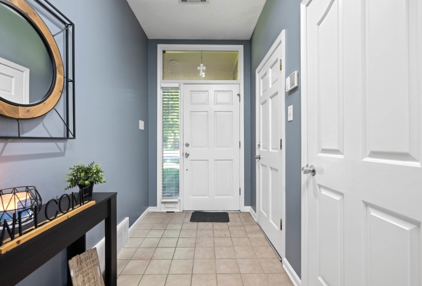 Entryway featuring neutral tile flooring, a white paneled door with sidelight and transom window, and a white six-panel interior door