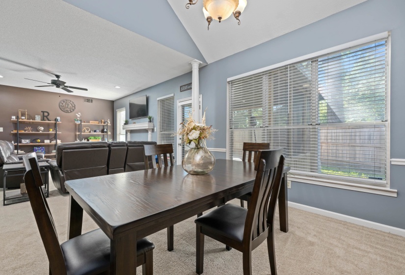 Dining area featuring a vaulted ceiling and a large window with blinds