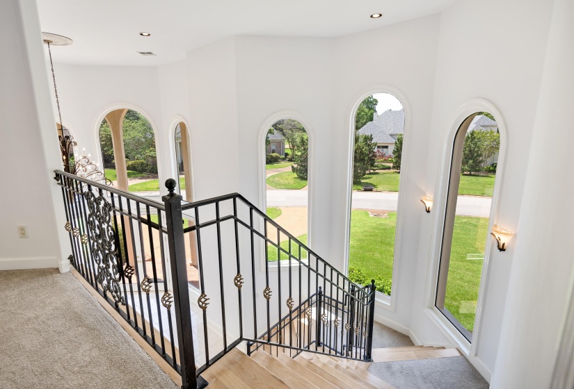 Staircase with ornamental wrought iron railing and light wood-finish treads