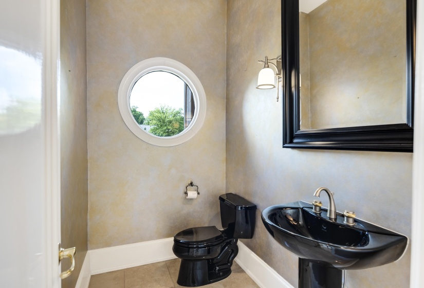 Powder room featuring a circular window, pedestal sink, and wall-mounted vanity light