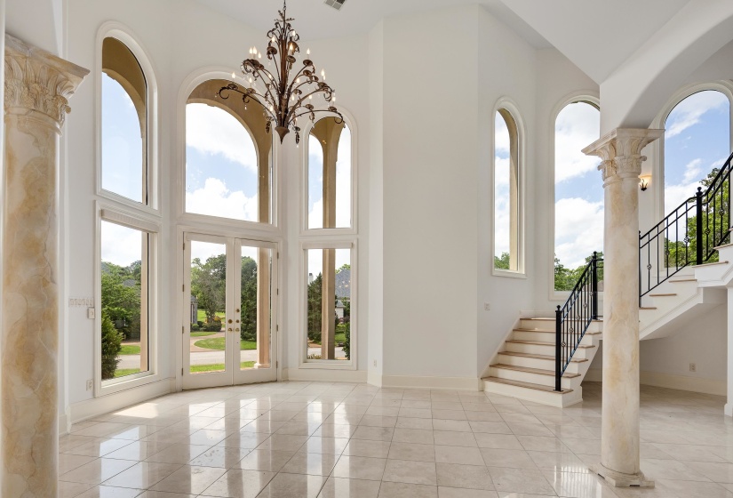 Grand entry featuring a dramatic two-story ceiling, arched windows, and tile flooring