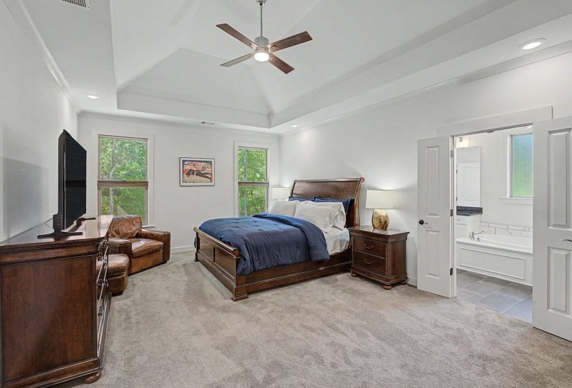 Spacious bedroom with a tray ceiling, recessed lighting, and a ceiling fan