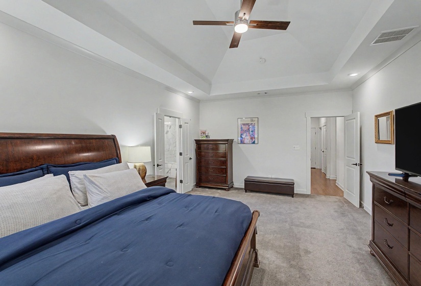Spacious bedroom featuring a tray ceiling with a ceiling fan, recessed lighting, and soft gray carpeting
