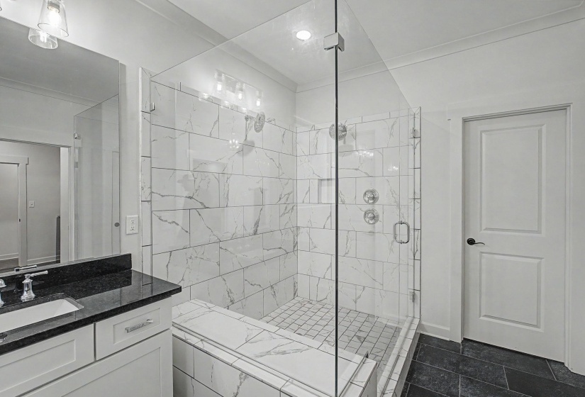 Glass-enclosed shower with subway tile surround, integrated bench, and dual shower heads