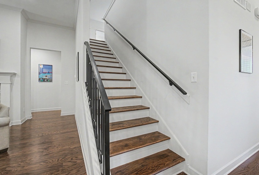 Staircase featuring dark wood-finish treads, white risers, and a black metal railing