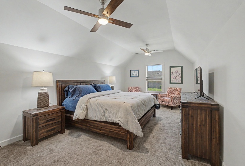 Spacious room featuring vaulted ceilings, two ceiling fans, and neutral-toned carpeting