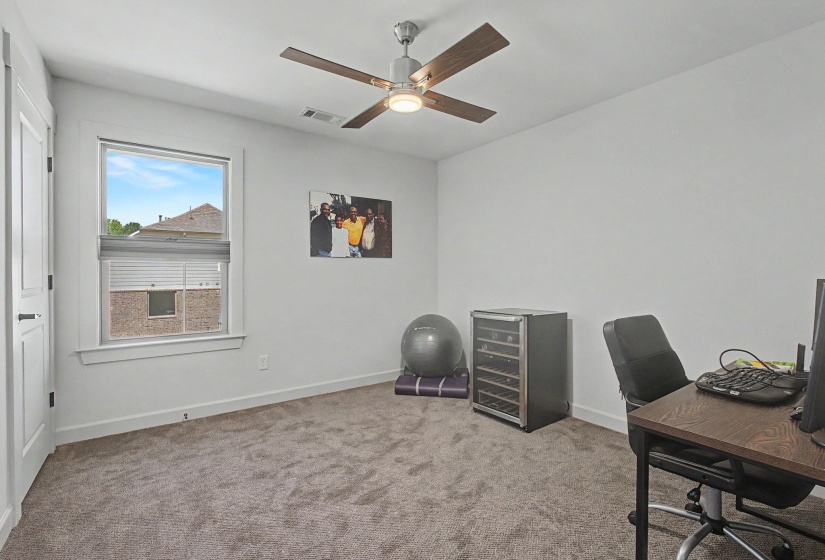 Spacious room featuring neutral carpeting, white walls, and a modern ceiling fan with wood-finish blades