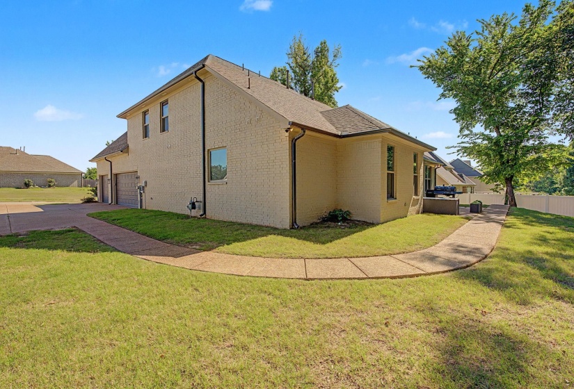 Exterior featuring light-colored brick siding, a multi-car garage, and a concrete driveway