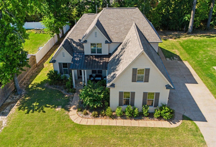 Modern two-story residence with a multi-gabled roofline and a covered front porch featuring a metal roof