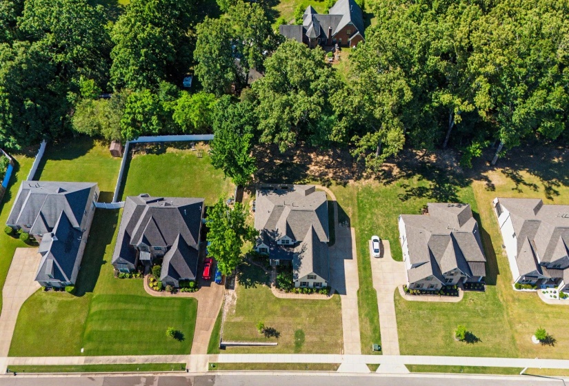 Aerial perspective showcasing multiple properties with manicured lawns and mature tree lines
