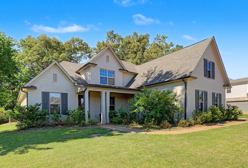 Traditional-style residence featuring a prominent gabled roofline, light-colored brick exterior, and dark louvered shutters