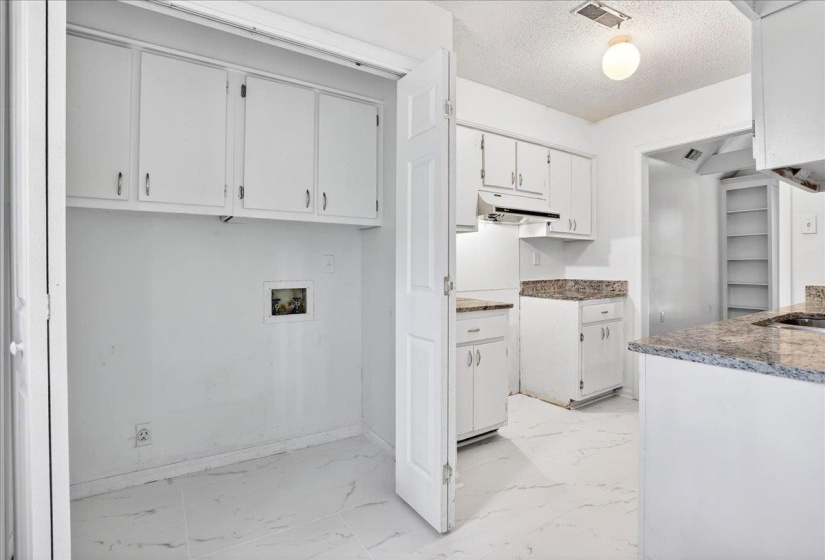 Kitchen area featuring white cabinetry, stone countertops, and tile flooring