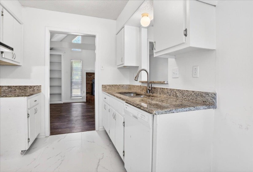 Kitchen featuring white cabinetry with brushed nickel hardware, granite countertops, and a stainless steel sink with a gooseneck faucet