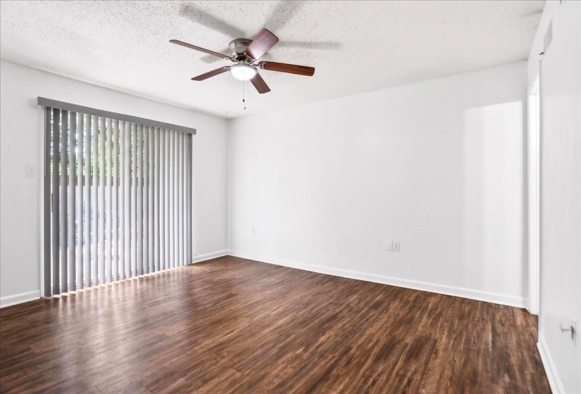 Spacious room featuring wood-finish flooring and a ceiling fan with integrated lighting