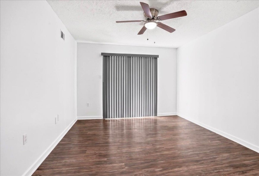 Spacious room featuring wood-finish flooring, white walls, and white baseboards