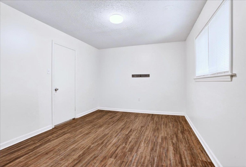 Room featuring wood-finish flooring, white walls, and a recessed window with blinds