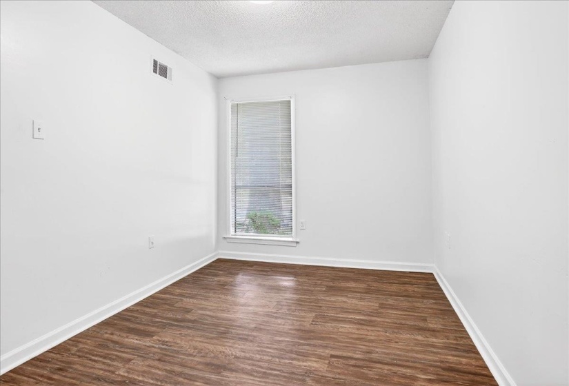 Interior room featuring wood-finish flooring, white baseboards, and bright white walls