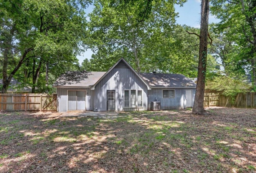 Spacious backyard with mature trees, a wood privacy fence, and a concrete patio
