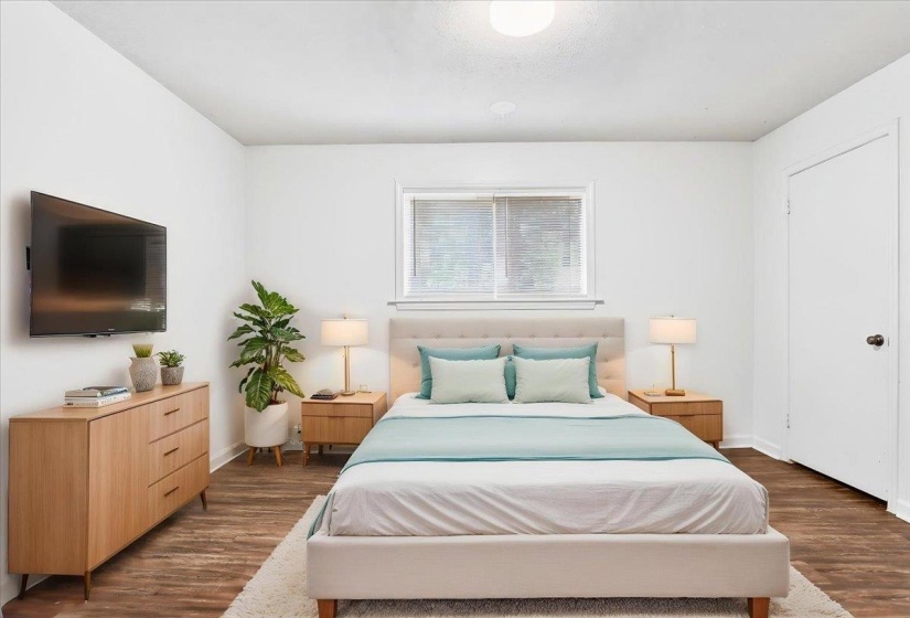Room featuring wood-finish flooring, a neutral wall color, and a window with blinds (Staged0