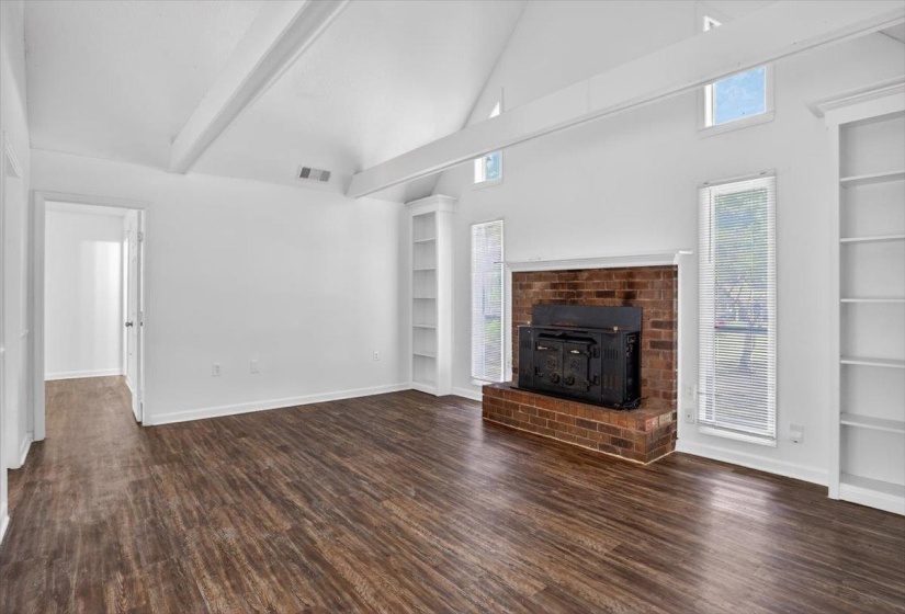 Vaulted ceiling with exposed beams over wood-finish flooring