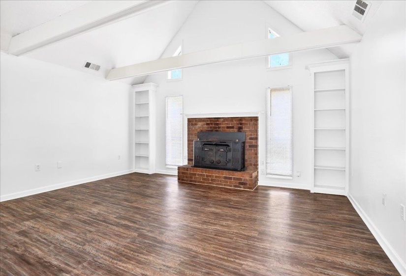 Vaulted ceiling with exposed white beams and wood-finish flooring