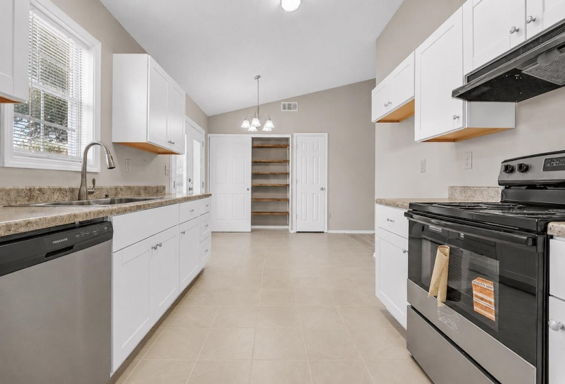 Open-concept kitchen featuring white cabinetry, stone-finish countertops, and stainless steel appliances