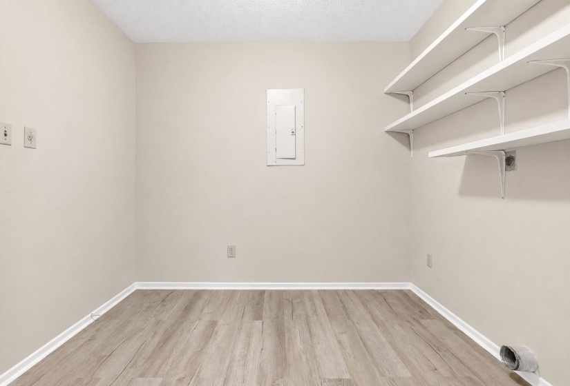 Utility room featuring wood-finish flooring, light neutral walls, and three built-in wall shelves