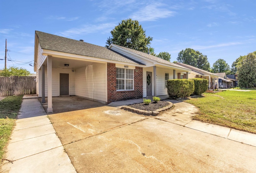 Front exterior featuring brick and horizontal siding, a covered carport, and a concrete driveway