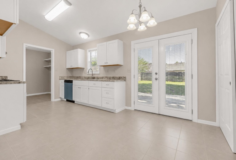 Kitchen featuring white cabinetry, light-toned tiled flooring, granite-look countertops, and a stainless steel sink with a gooseneck faucet