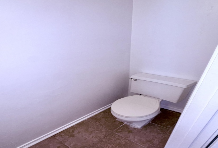 Powder room featuring a ceramic toilet and durable tile flooring
