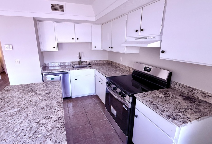 Kitchen featuring an electric range, stainless steel dishwasher, white cabinetry, and light-toned countertops