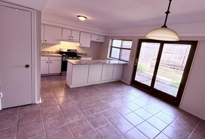 Kitchen featuring white cabinetry, light-toned countertops, a central island, stainless steel range, and tile flooring
