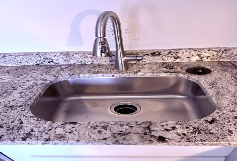 Stainless steel undermount sink with a brushed nickel pull-down faucet and granite-finish countertop