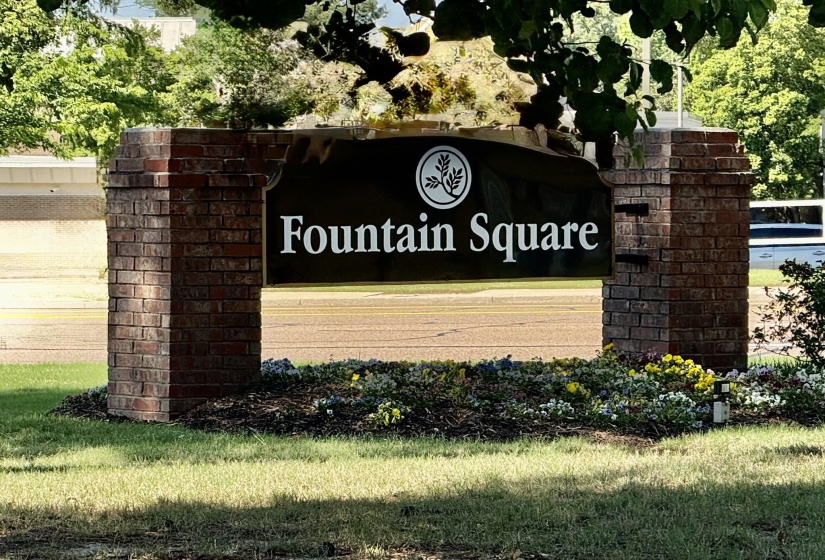 Community signage featuring brick pillars and a dark-toned sign with 