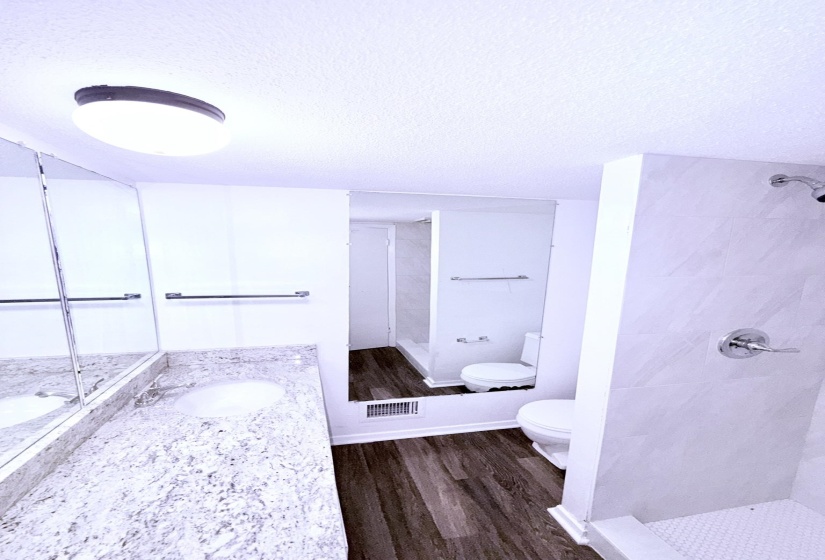 Bathroom featuring a granite-style countertop, integrated sink, and large wall-mounted mirror