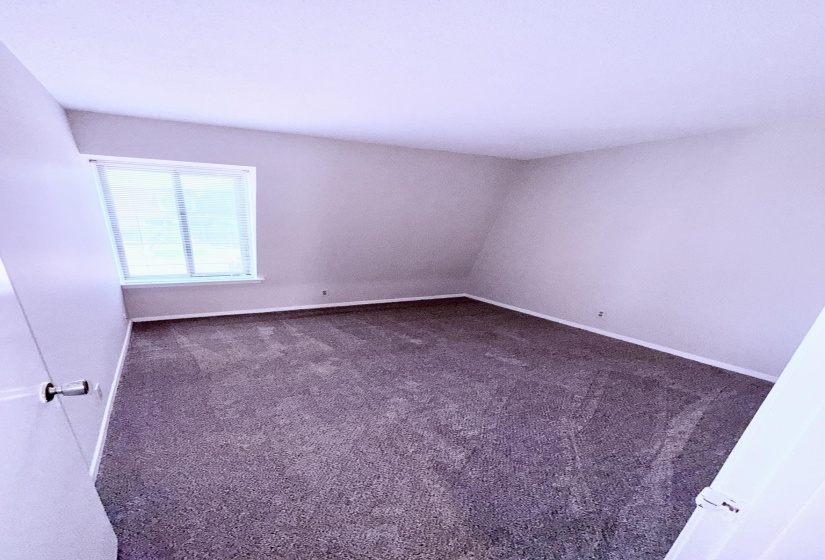 Room featuring neutral-toned walls, dark gray carpet, white baseboards, and a window with horizontal blinds