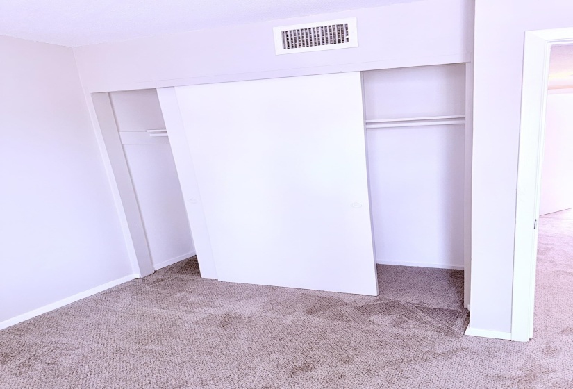 Bedroom featuring a wall-to-wall closet with white sliding doors, integrated shelving, and hanging rods