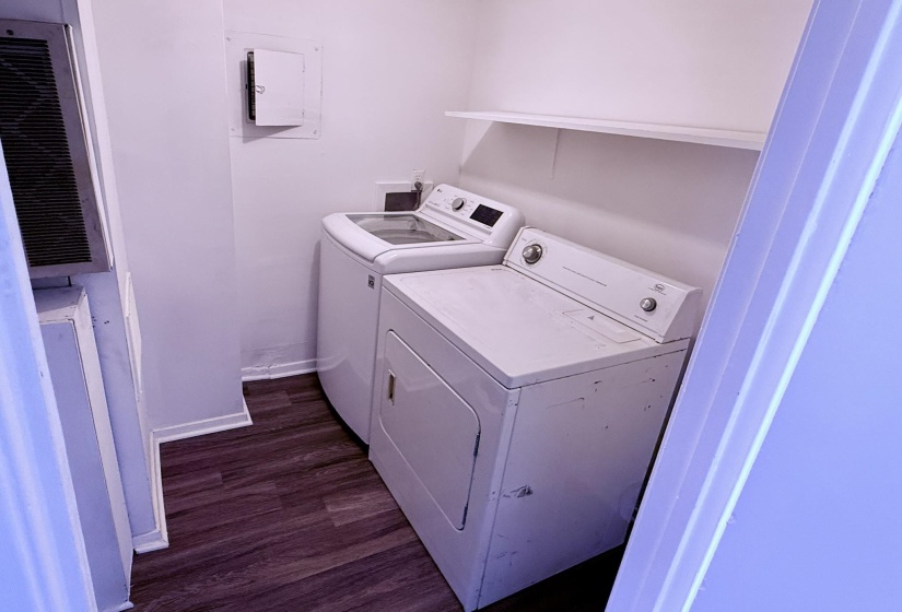 Laundry area featuring white walls, wood-finish flooring, a white floating shelf, and baseboard trim