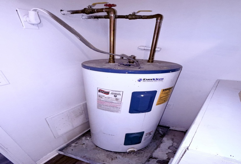 White water heater with brass plumbing connections and a white wall vent
