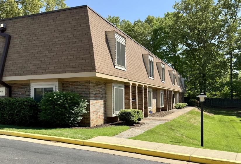 Brown brick facade with a mansard roof, multiple dormer windows, and a paved walkway