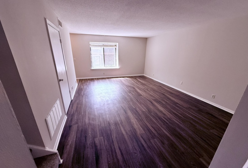 Spacious room featuring dark wood-finish flooring, light neutral walls, and white trim