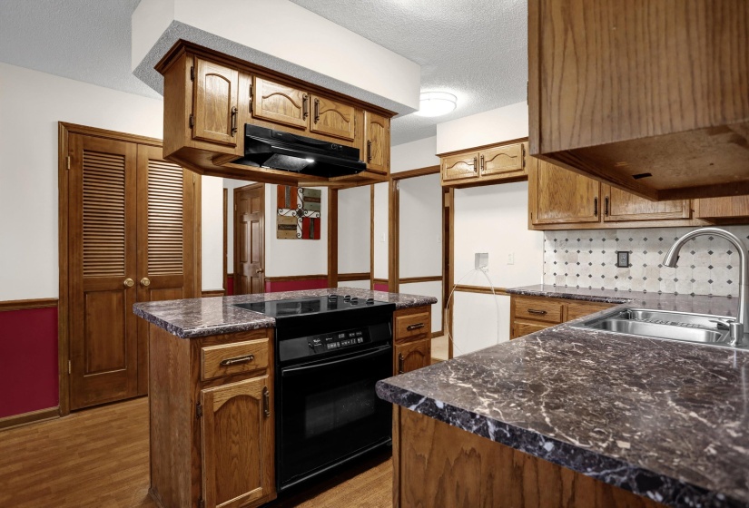 Kitchen featuring wood cabinetry and dark stone-finish countertops
