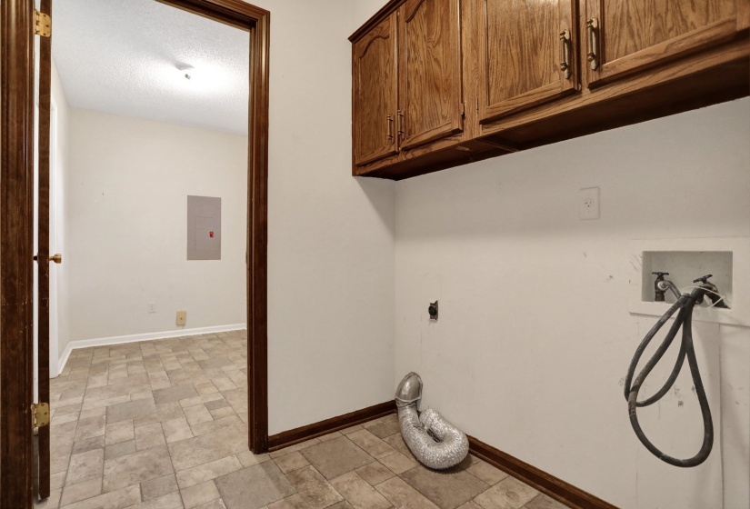Utility area featuring wood-finish cabinetry, tile flooring, and integrated washer hookups