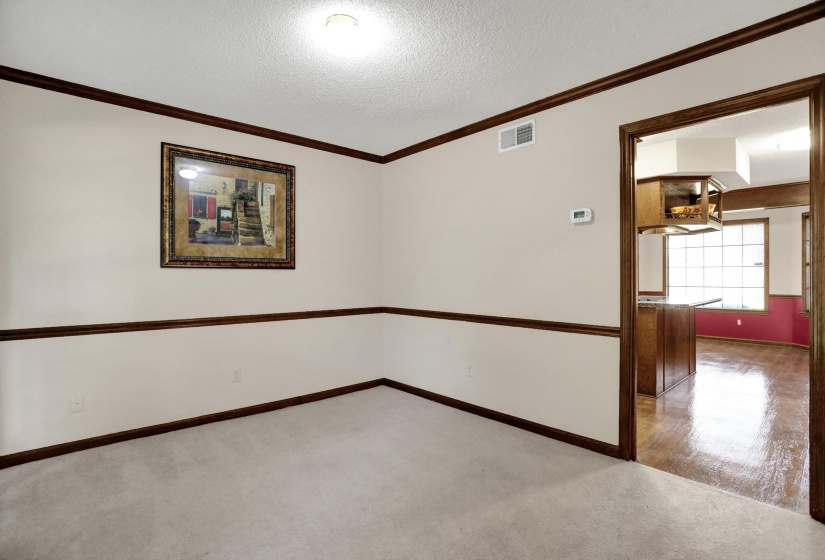 Neutral wall paint with dark wood-finish trim and crown molding
