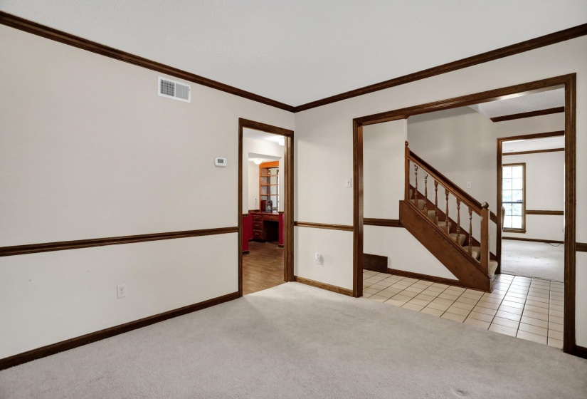 Interior featuring light-colored walls with dark wood trim, carpeted flooring, and a tiled entryway