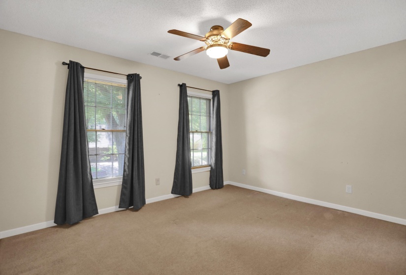 Carpeted room with a ceiling fan light fixture and two windows