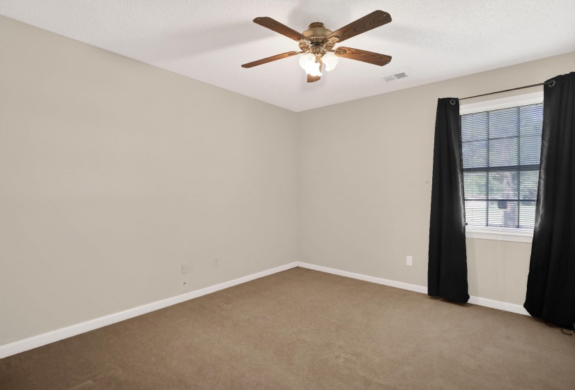 Neutral-toned interior room featuring carpeted flooring and a window with blinds